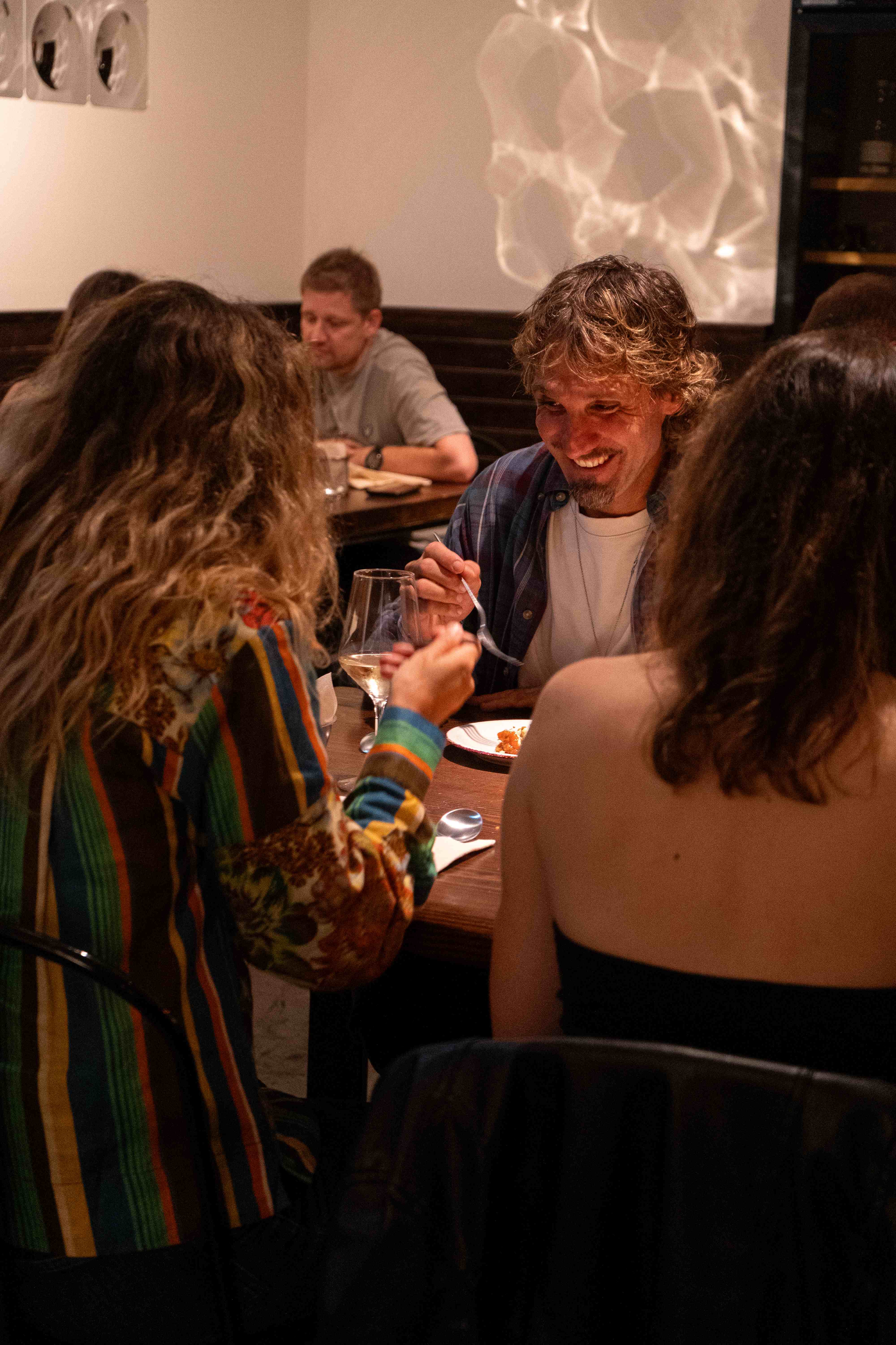 Personas compartiendo una comida y conversando en una mesa de Oltre
